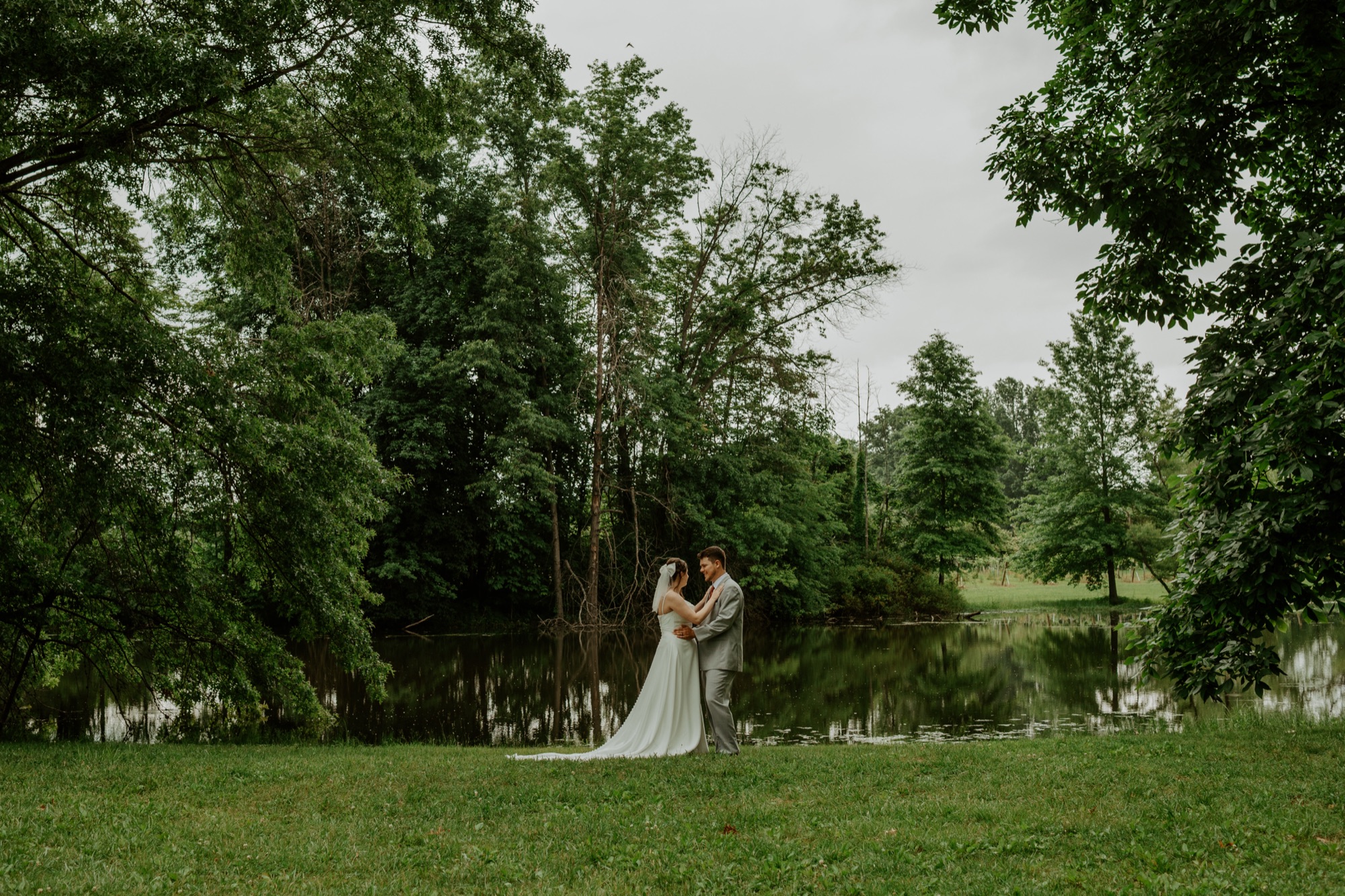 Couple by the pond among the trees at Abram Farms