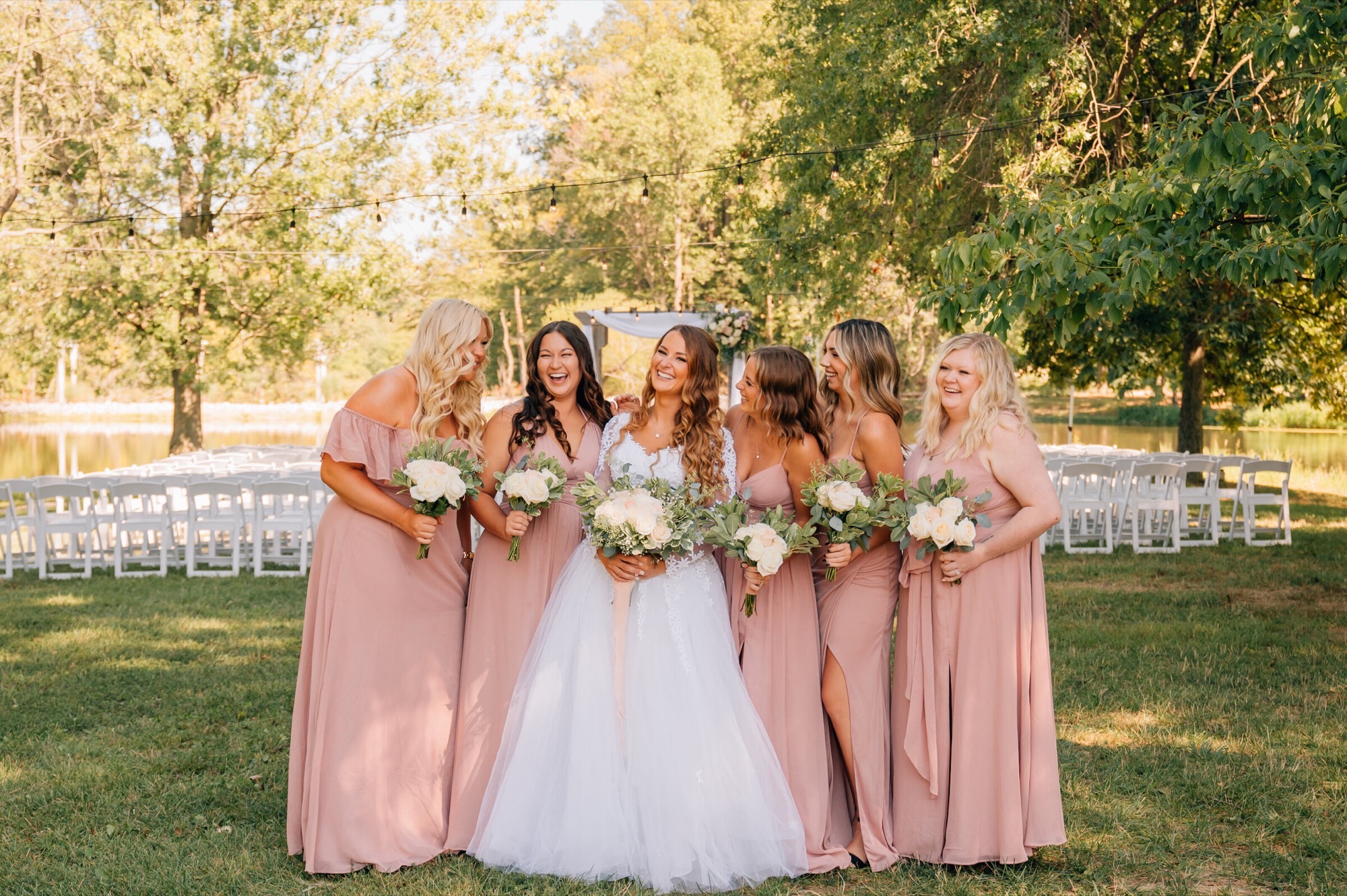Bride and bridesmaids by the pond ceremony site at Abram Farms